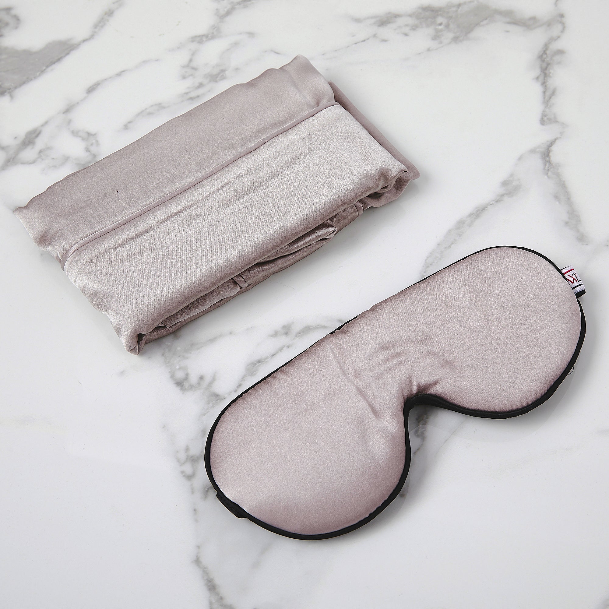 A pearl grey mulberry eye mask and pillowcase on a marble background