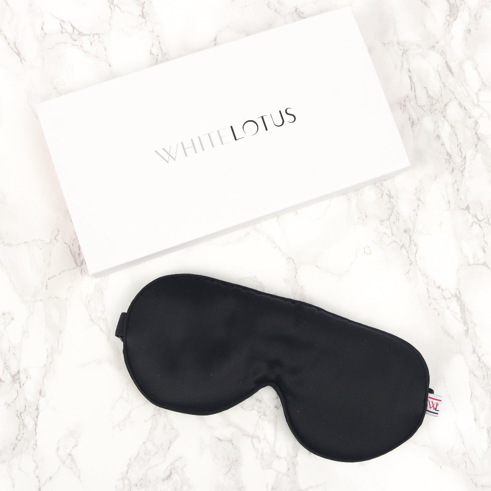 A black mulbery silk eye mask on a marble background with a box