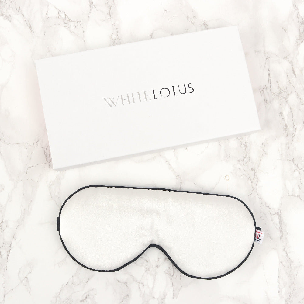 A white silk eye mask on a marble lifestyle background